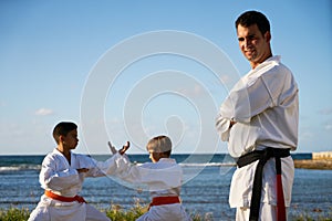 Portrait Of Confident Karate Trainer Watching Children Fight