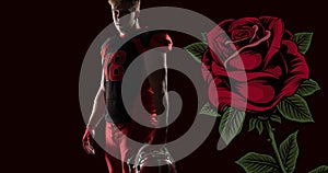 Portrait of confident male american footballer holding helmet by rose against black background