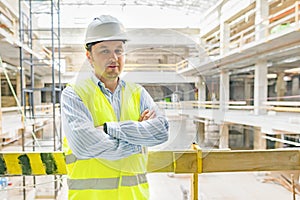 Portrait of confident male builder, manager, engineer with folded hands on construction site. Building, development concept