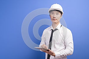 Portrait of confident male engineer wearing a white using tablet over blue background studio
