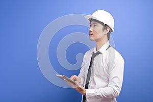 Portrait of confident male engineer wearing a white using tablet over blue background studio