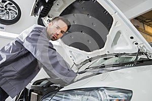 Portrait of confident male repair worker repairing car engine in repair shop