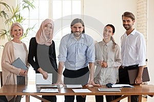 Portrait of confident male team leader with smiling diverse colleagues.