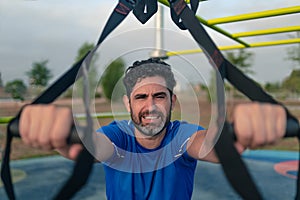 Portrait of confident man doing fitness exercises on a special hanging device