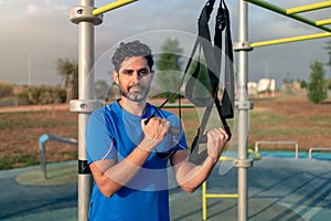 Portrait of confident man doing fitness exercises on a special hanging device