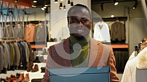 Portrait of confident man with shoe boxes in clothing store. A man buying shoes in the store