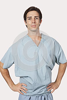 Portrait of confident man in surgical scrubs standing against gray background