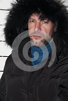 Portrait of confident man wearing fur hooded parka coat at the w