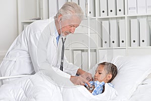 Portrait of confident mature doctor inspecting little patient