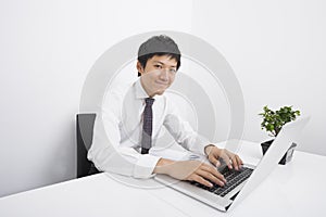 Portrait of confident mid adult businessman using laptop at office desk