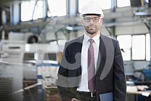 Portrait of confident mid adult businessman wearing hardhat in metal industry