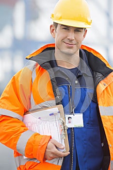 Portrait of confident mid adult man with clipboard in shipping yard