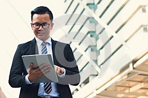 Portrait of confident modern young businessman wear black suit hand holding digital tablet. Professional business man