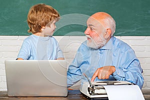 Portrait of confident old male teacher. Teacher helping his teen pupil on education class. Young boy doing his school