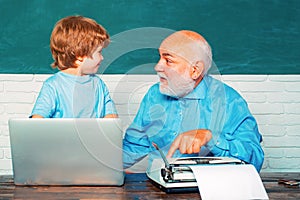 Portrait of confident old male teacher. Teacher helping his teen pupil on education class. Young boy doing his school