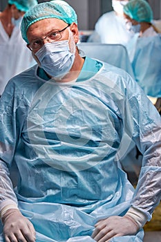 Portrait of confident professional male surgeon posing at camera in medical room