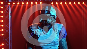 Portrait of confident quarterback agressive looking at camera. American football player in team uniform and helmet