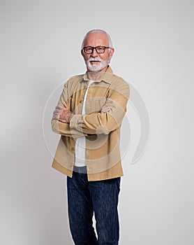 Portrait of confident senior businessman with arms crossed standing on isolated white background