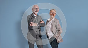 Portrait of confident senior businessman and businesswoman wearing elegant formal wear and posing with arms crossed and hands in