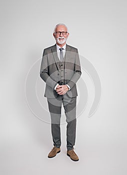 Portrait of confident senior businessman with glasses smiling at camera on isolated white background