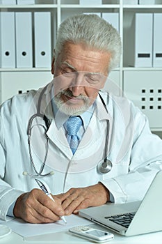 Portrait of confident senior male doctor working in office