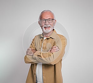 Portrait of confident senior male manager with arms crossed smiling at camera on white background