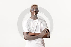Portrait of confident and serious african-american blond guy wearing sunglasses and cross arms chest, acting sassy and