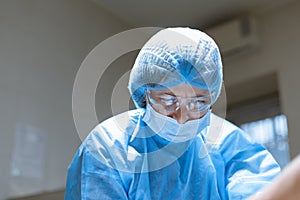 Portrait confident serious female surgeon in surgical room hospital, medical doctor wear surgery suit and protective glasses