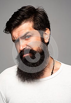 Portrait of confident serious man has beard and mustache, looks seriously, isolated. Hipster guy models in studio