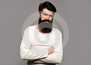 Portrait of confident serious man has beard and mustache, looks seriously, isolated. Hipster guy models in studio