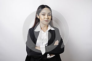 Portrait of a confident smiling Asian girl boss wearing black suit standing with arms folded and looking at the camera isolated