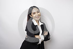 Portrait of a confident smiling Asian girl boss wearing black suit standing with arms folded and looking at the camera isolated
