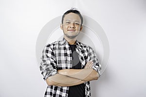 Portrait of a confident smiling Asian man wearing tartan shirt standing with arms folded and looking at the camera isolated over