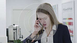 Portrait of a confident smiling beautiful business woman or secretary in a business strict suit talking on a cell phone