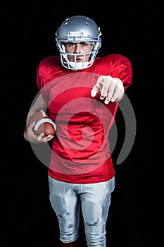 Portrait of confident sportsman pointing while holding American football