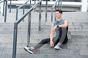 Portrait of a confident sporty man. Young sportsman sitting outdoors after good jogging workout. Young man in sportswear