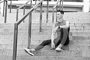 Portrait of a confident sporty man. Young sportsman sitting outdoors after good jogging workout. Young man in sportswear
