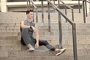 Portrait of a confident sporty man. Young sportsman sitting outdoors after good jogging workout. Young man in sportswear