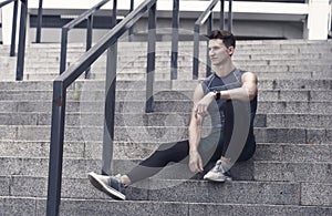 Portrait of a confident sporty man. Young sportsman sitting outdoors after good jogging workout. Young man in sportswear