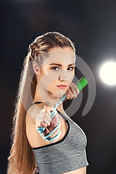 Portrait of confident sporty woman holding skipping rope