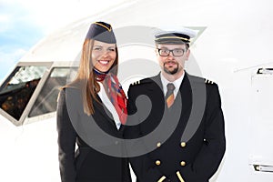 Portrait of confident stewardess and pilot standing against plane