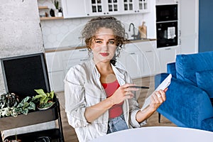 Portrait of confident stylish business woman is making notes, looking at the camera, smiling. Successful young female