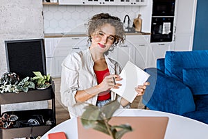 Portrait of confident stylish business woman is making notes, looking at the camera, smiling. Successful young female