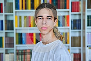 Portrait of a confident teenage boy looking at the camera in the library.