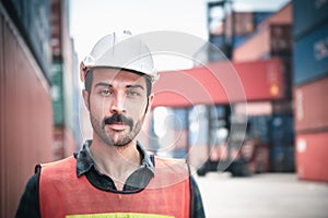 Portrait of Confident Transport Engineer Man in Safety Equipment Standing in Container Ship Yard. Transportation Engineering