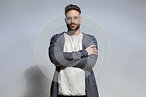 Portrait of confident unshaved man with glasses crossing arms