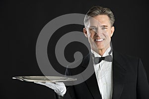 Portrait Of Confident Waiter In Tuxedo With Serving Tray