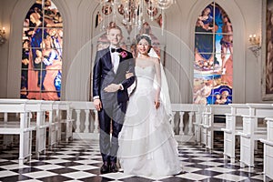 Portrait of confident wedding couple standing arm in arm at church