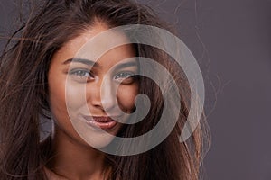 Portrait, confident woman or messy hair in wind, damage or treatment in studio on grey background. Grooming, frizz and
