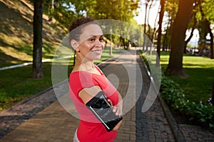 Portrait of a confident 40 years old African American woman in sportswear standing in forest city park with her arms crossed and